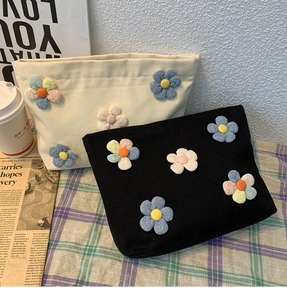 Detailed view of canvas makeup bags featuring 3D handmade floral ornaments in black and beige