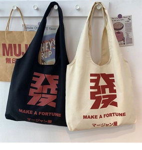Detail of canvas tote bags in black and beige with fortune text and durable long handles