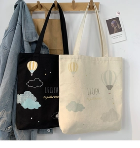 Detail view of canvas tote bags with Lucien hot air balloon print hung on wooden hooks