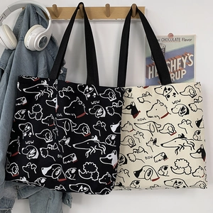 Detail of canvas tote bag with hand-drawn dog illustrations and black strap handles