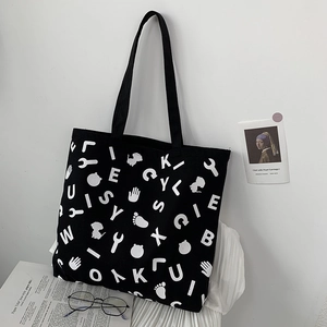 Large black canvas tote bag with white letter print and durable shoulder straps
