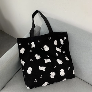 Gros plan sur un cabas en toile noire avec motifs de chiots blancs et notes de musique
