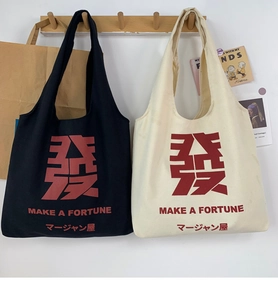 Detail view of Mahjong themed canvas tote bags in black and beige hanging on wooden hooks