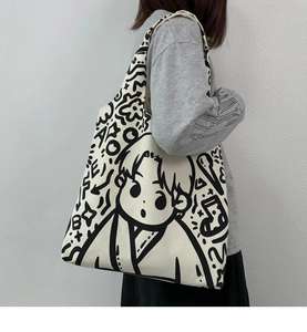 Large cream canvas tote bag with cartoon sketch carried by a model on shoulder