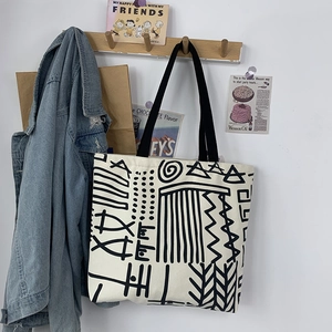 Artistic canvas tote bag hanging on hook showing abstract geometric pattern and strap detail