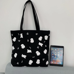 Détail d'un sac cabas en toile noire avec motifs de chiens et tablette pour taille réelle