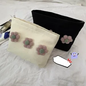 Detail view of canvas makeup bags featuring 3D floral accents and top zipper closure