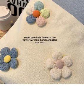 Detail of fixed plush 3D flowers on beige canvas cosmetic bag with rich fabric texture