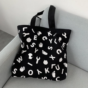 Detail of black canvas tote bag showing white cartoon prints and durable fabric texture