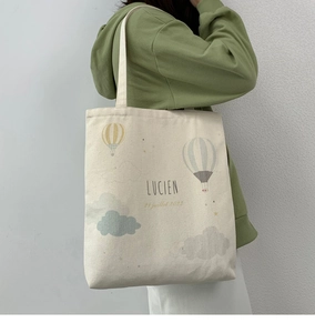 Detail of canvas tote bag with hand-drawn hot air balloon pattern and artistic text