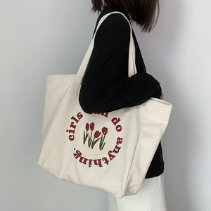 Detail of canvas tote bag featuring red tulip print and girls can do anything text