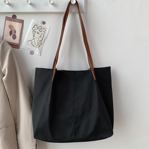 Close-up of minimalist black nylon tote bag with brown faux leather shoulder straps