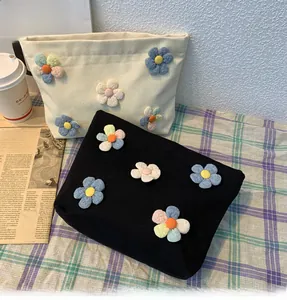 Close-up of canvas makeup bags with 3D floral appliques in black and cream white finish
