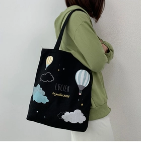 Side view of black canvas tote bag featuring Lucien hot air balloon and star prints