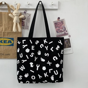 Detail of black canvas tote bag featuring white letter prints and casual shoulder straps