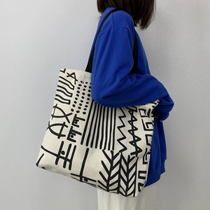 Side view of a large canvas tote bag with black geometric patterns on a female model