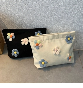 Detail view of canvas makeup bags with colorful 3D fabric flowers in black and beige