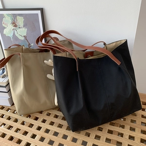 Detail of minimalist canvas tote bags in black and beige with leather shoulder straps