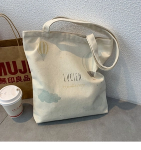 Close-up of minimalist cream canvas tote bag with hot air balloon print and Lucien text