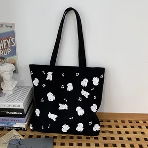Détail de chiens blancs mignons et de notes de musique sur un sac cabas en toile noir