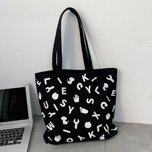 Detail of black canvas tote bag with white graphic prints and laptop accessory