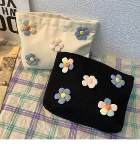 Detail of canvas makeup bags featuring colorful 3D handmade floral appliques and textures