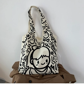 Detail of off-white canvas tote bag with black cartoon graffiti and durable double handles