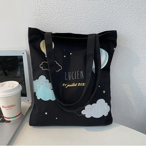 Detailed view of black canvas tote bag with colorful hot air balloon illustration and text