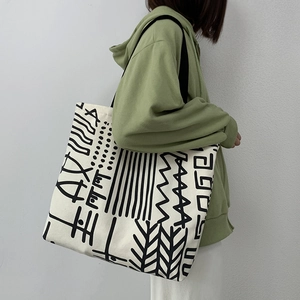 Detail of the cream canvas tote bag featuring black abstract artistic tribal patterns