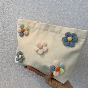 Detail view of large canvas makeup bag featuring 3D colorful floral patches