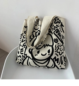 Detail of off-white canvas tote bag featuring black graffiti art and LOVE print on a chair