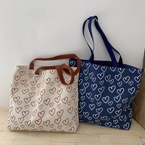 Detail of canvas tote bags with heart patterns in off-white and navy blue colors