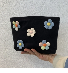 Detail of a black canvas makeup bag featuring vibrant 3D fabric flower decorations