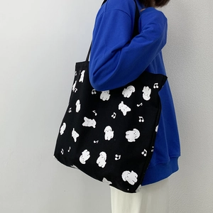 Détail du sac cabas en toile noir avec imprimés mignons de chiots et notes de musique