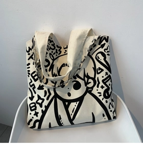 Detail of canvas tote bag featuring artistic black hand-drawn graffiti and anime motifs