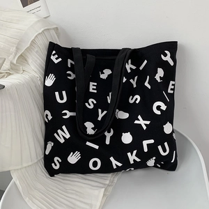 Detail of a large black canvas tote bag featuring white pop art graphic prints and letters
