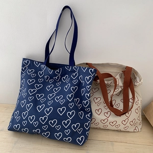 Detail of canvas tote bags with heart patterns and reinforced woven shoulder straps