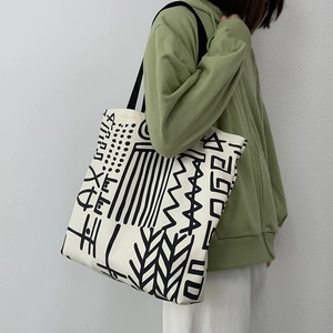 Close-up of white canvas tote bag with abstract black patterns on model shoulder