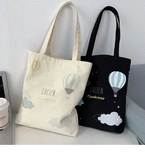 Detail of canvas tote bags in cream and black featuring hot air balloon screen print
