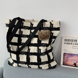 Detail of a large canvas tote bag with black and white check pattern and a small bear charm