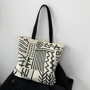 Close-up of minimalist canvas tote with black abstract patterns and fabric handles