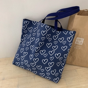 Detail view of navy blue canvas tote bag featuring white heart print and webbing handles