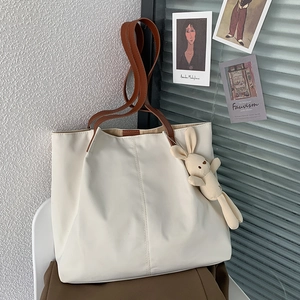 Close-up of cream canvas tote bag with brown straps and cute rabbit plush charm