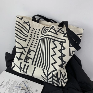 Detail of canvas tote bag with black geometric patterns and thick shoulder straps