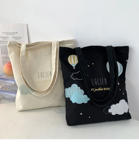 Close-up of hot air balloon print and artistic lettering on canvas tote bags