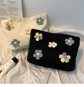 Detail of canvas floral makeup bags in beige and black with 3D colorful flower accents