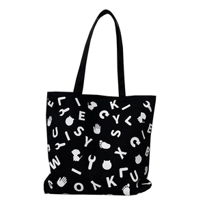 Black canvas tote bag with white graphic letter print and long shoulder straps