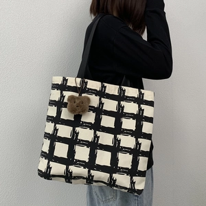 Detail shot of black and white checkered canvas tote bag with a cute plush bear pendant