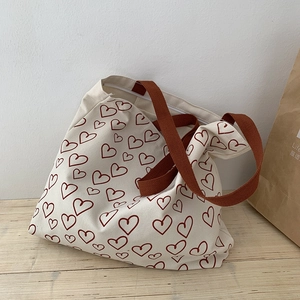 Detail of canvas tote bag with brown heart pattern and secure zipper closure on wooden desk