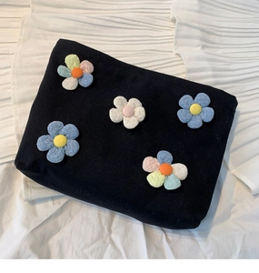 Detail of five 3D colorful fabric flowers on a black canvas portable makeup bag